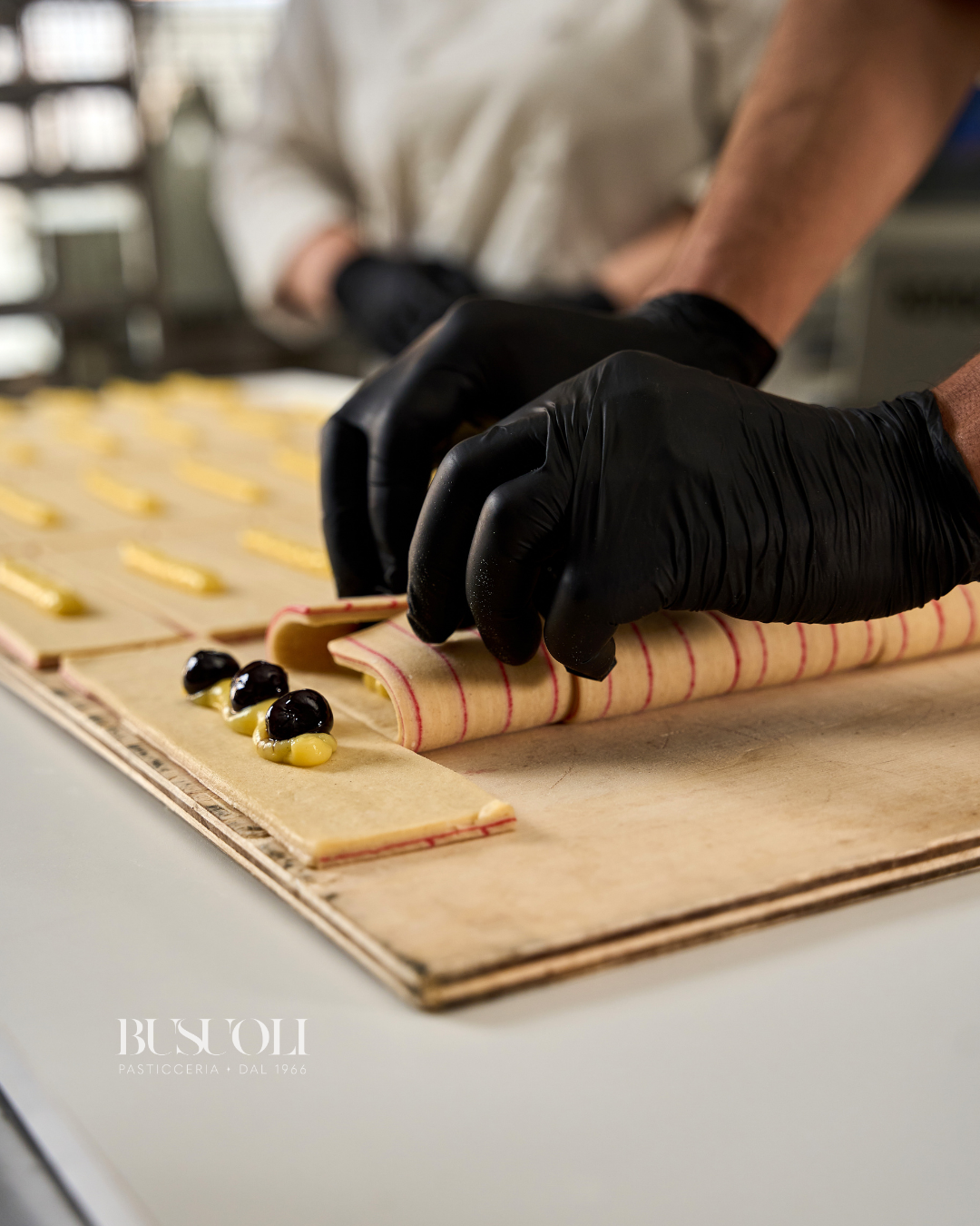 Preparazione pain suisse crema e amarene nel laboratorio di pasticceria busuoli mirandola